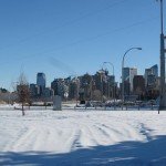 snowy foreground, blue sky, city of Calgary buildings in distance